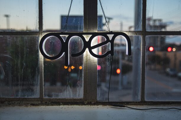 Hinterleuchteter Schriftzug „open“ an einem industriellen Sprossenfenster angebracht