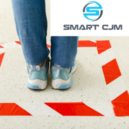 Ein Mensch, sichtbar nur die Beine in Jeans und Turnschuhen, wartet in einer Markierung. Logo Smart CJM